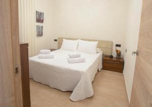 a bedroom with a white bed with towels on it at Chalet Torredembarra Aire Acondicionado zona muy Tranquila in Torredembarra