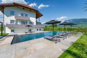 a villa with a swimming pool and umbrellas at Ferienwohnungen Zwerger Reinhold in Termeno