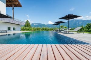 a swimming pool with benches and umbrellas next to a house at Ferienwohnungen Zwerger Reinhold in Termeno