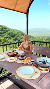 a woman sitting at a picnic table with food on it at Dream Domes Luxury Glamping Tents in Gabala
