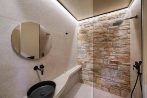 a bathroom with a black sink and a stone wall at Brothers Studios & Suites in Skala Potamias +42 photos