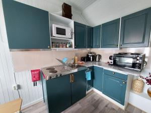 a kitchen with blue cabinets and a sink and a microwave at The Perfect Stop - 3rd floor Apartment in Lødingen +34 photos