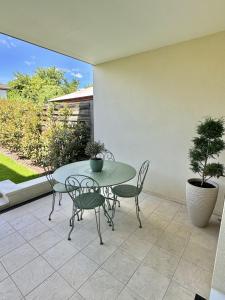 un patio con tavolo, sedie e una pianta in vaso di Appartement terrasse et jardin a Saint-Julien-les-Villas Altre 3 foto