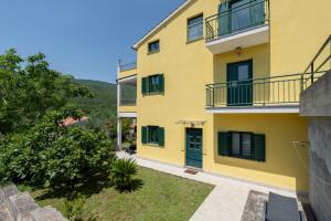 a yellow building with green doors and a yard at HAUS RITA in Labin
