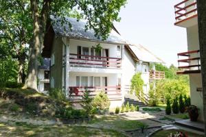 a white house with a porch and a balcony at FALEZA Dębina in Debina