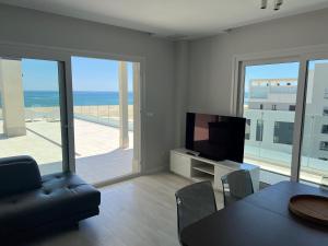 a living room with a television and a table and chairs at New penthouse with sunny beach view in Huelva