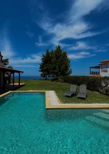a swimming pool with two chairs next to a house at Sunset Villa Elani in Elani