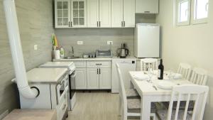 a kitchen with white cabinets and a white table and chairs at Vila Tamara 2024 in Žabljak