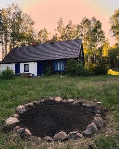 ein Haus auf einem Feld mit einem Steinkreis davor in der Unterkunft 24mousehouse - Urokliwy domek w sercu Borów Tucholskich in Czersk Pomorski
