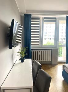 a living room with a table and chairs and a tv at Doba Rent POKOJE CENTRUM PAŁACOWA in Białystok