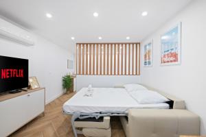 Una habitación blanca con una cama y un televisor. en La perle, en Menton