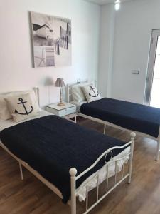 Un dormitorio con dos camas y una mesa con lámpara. en Lovely & New BEACH APARTMENT, en Atouguia da Baleia