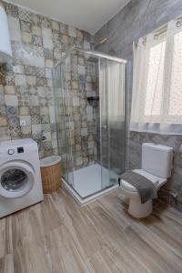 ein Bad mit einer Dusche, einem WC und einer Waschmaschine in der Unterkunft Brand new Apartament in Marsalforn in Żebbuġ + 14 Fotos