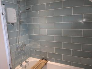 La salle de bains est pourvue d'une baignoire et d'une douche avec du carrelage bleu. dans l'établissement 5 Edgebury, à Puriton 14 autres photos