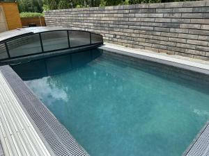 a swimming pool in front of a brick wall at Apartmán Oliva in Horní Planá