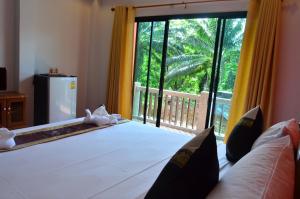 a bedroom with a bed and a large window at Phongpipat Lanta Mansion in Ko Lanta