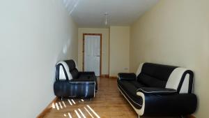 sala de estar con 2 sillas de cuero y sofá en The Serenity Apartment, en Mánchester