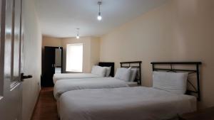 1 dormitorio con 2 camas con sábanas blancas y ventana en The Serenity Apartment, en Mánchester