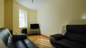 Una sala de estar con un sofá de cuero y un televisor. en The Serenity Apartment, en Mánchester