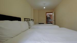 Dos camas en un dormitorio con sábanas blancas. en The Serenity Apartment, en Mánchester