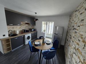 a kitchen with a table and blue chairs in a room at Emiri Apartament in Hunedoara
