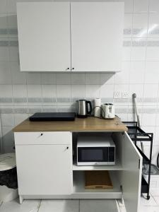 eine Küche mit weißen Schränken und einer Mikrowelle in der Unterkunft Al Salehiyah 2 in Medina