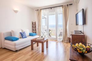 a living room with a white couch and a table at Zlatni Bol Apartments in Bol