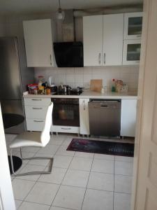 cocina con armarios blancos y suelo de baldosa blanca en Zimmer in eine whg in 63 rue des abeilles, en Mulhouse