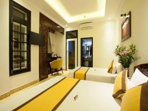 a hotel room with two beds and a desk at Hoi An Hai Au Boutique Hotel in Hoi An