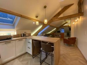 a kitchen with white cabinets and a bar with stools at Le Chalet Dieppois in Dieppe