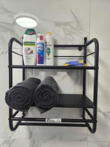 a black towel rack with towels and cleaning products at Studio style room, near Tooting Broadway station in London