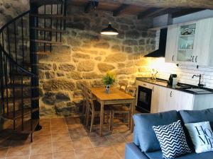 Una sala de estar con una mesa y una pared de piedra. en Casa Anduriña, en Ourense
