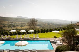 a swimming pool with chairs and umbrellas and a view at Borgo San Faustino Country Relais and Spa Orvieto in Orvieto