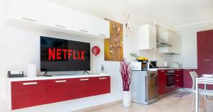 a kitchen with red cabinets and a tv on a wall at Oleandro Apartment - Featuring a Private Garden and Access to 5 Pools in Desenzano del Garda