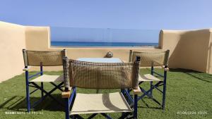 three chairs and a table on a balcony with the ocean at Niros Beachfront Aparthotel in Kokkíni Khánion