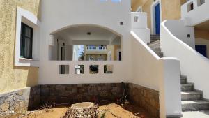 a building with white walls and a stairway at Niros Beachfront Aparthotel in Kokkíni Khánion