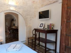 une chambre avec un lit et une télévision sur un mur dans l'établissement Case Vacanza La Vita A Cono, à Cisternino