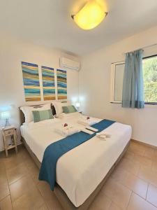 a bedroom with a large white bed with a blue blanket at Breeze Beach Apartment Glyfada in Corfu