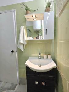 a bathroom with a sink and a mirror at Breeze Beach Apartment Glyfada in Corfu +30 photos