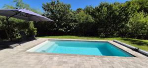 a swimming pool with an umbrella and a chair at "L'appart Idéal" in Deyme
