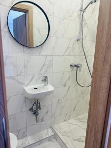 a white bathroom with a sink and a mirror at NB Apartamentai in Palanga