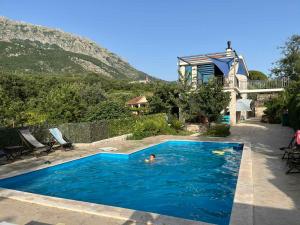 una persona nadando en una piscina con una casa en Stone Villa UK - Dobra Voda, en Bar