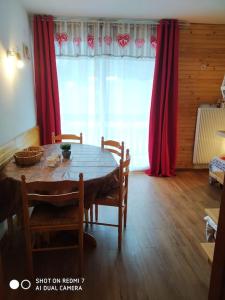 ein Esszimmer mit einem Tisch und roten Vorhängen in der Unterkunft STUDIO 6 PERS LE BOIS D'AUROUZE 2eme étage NORD in Superdevoluy