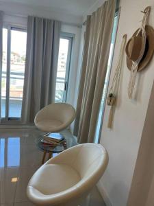 a living room with two white chairs and a window at Solares de araus, apartamento in Colonia del Sacramento