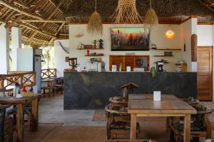 a restaurant with tables and chairs and a tv on the wall at Mambo Cabana in Pwani Mchangani