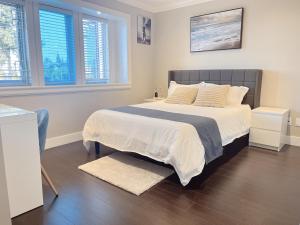 une chambre avec un grand lit avec des draps et des oreillers blancs dans l'établissement Near Skytrain and QUIET Private Bedroom Ensuite BathRM, Free Wifi & Coffee, Cozy, à Burnaby