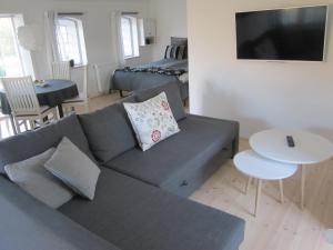 a living room with a gray couch and a bed at Tåsinge B&B in Svendborg