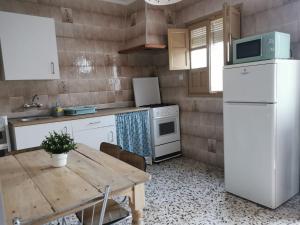a kitchen with a wooden table and a white refrigerator at Casa Rural La Barranca in Cuevas del Becerro