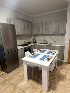 a kitchen with a white table with chairs and a refrigerator at Adrian Apartment in Orikum +2 photos
