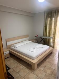 a bedroom with a bed with white sheets and a table at Adrian Apartment in Orikum